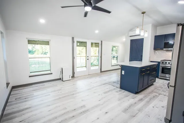 a living room with stainless steel appliances kitchen island granite countertop furniture and a wooden floor