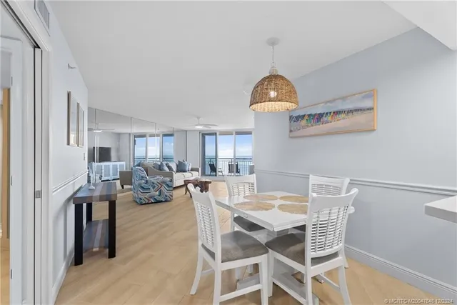 a view of a dining room and livingroom with furniture wooden floor a rug and a chandelier