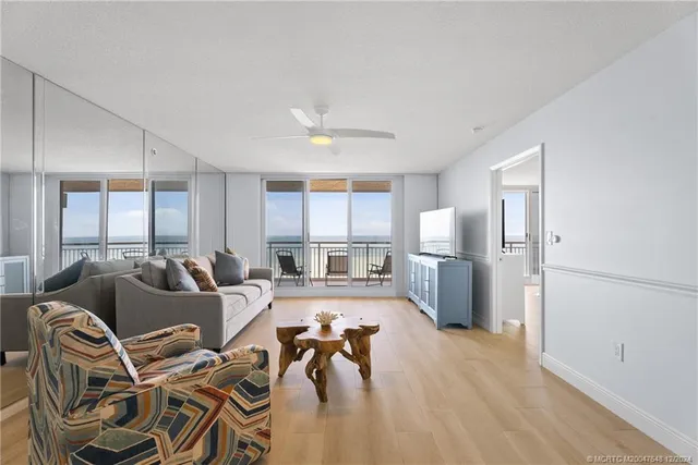 a living room with furniture a large window and stainless steel appliances