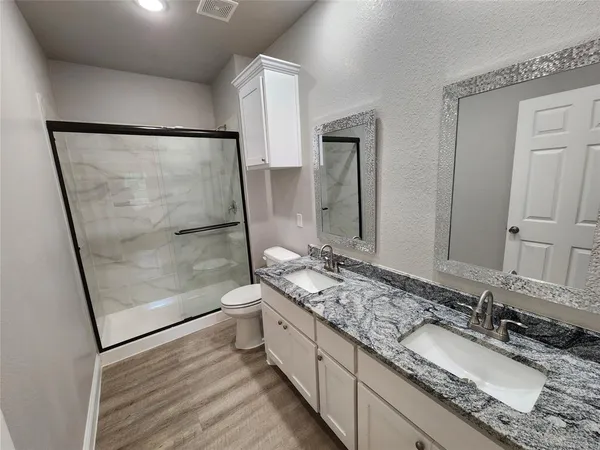 a bathroom with a granite countertop sink a mirror and a shower