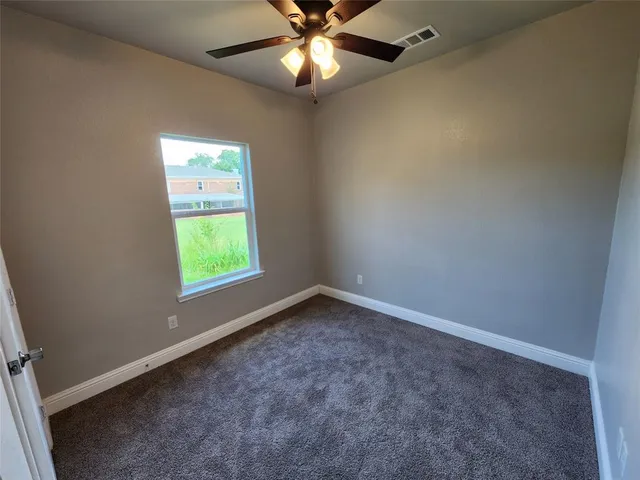 an empty room with a window and a fan