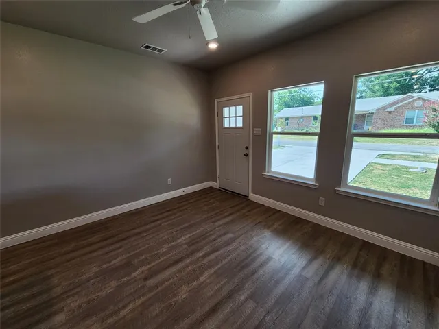 an empty room with wooden floor and windows