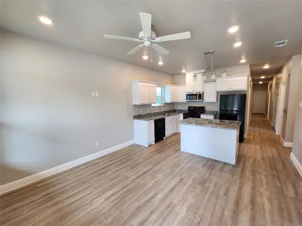 a large kitchen with granite countertop a stove top oven a sink dishwasher and a fireplace with wooden floor