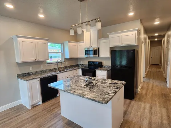 a kitchen with kitchen island stainless steel appliances a sink stove and refrigerator