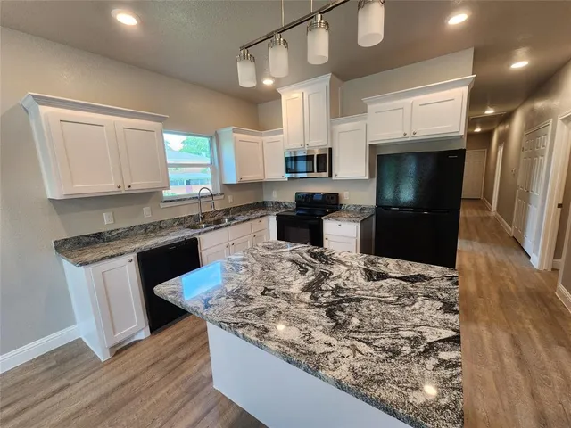 a kitchen with stainless steel appliances kitchen island granite countertop a sink stove and refrigerator