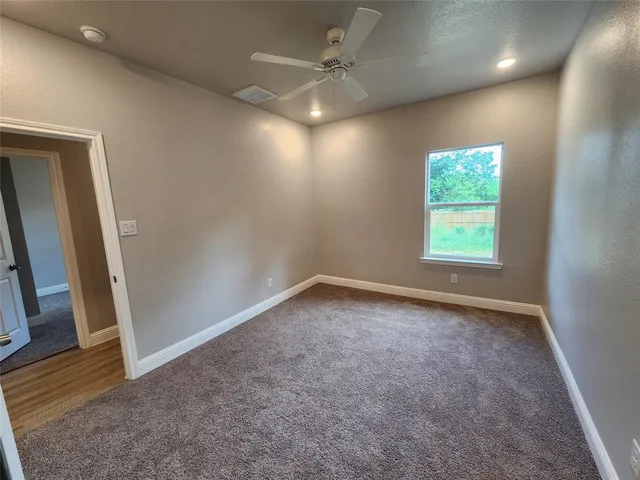 an empty room with a window and a fan