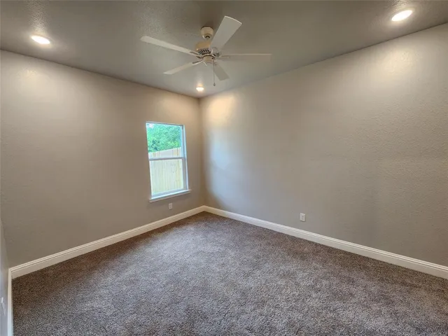 an empty room with a chandelier fan and windows