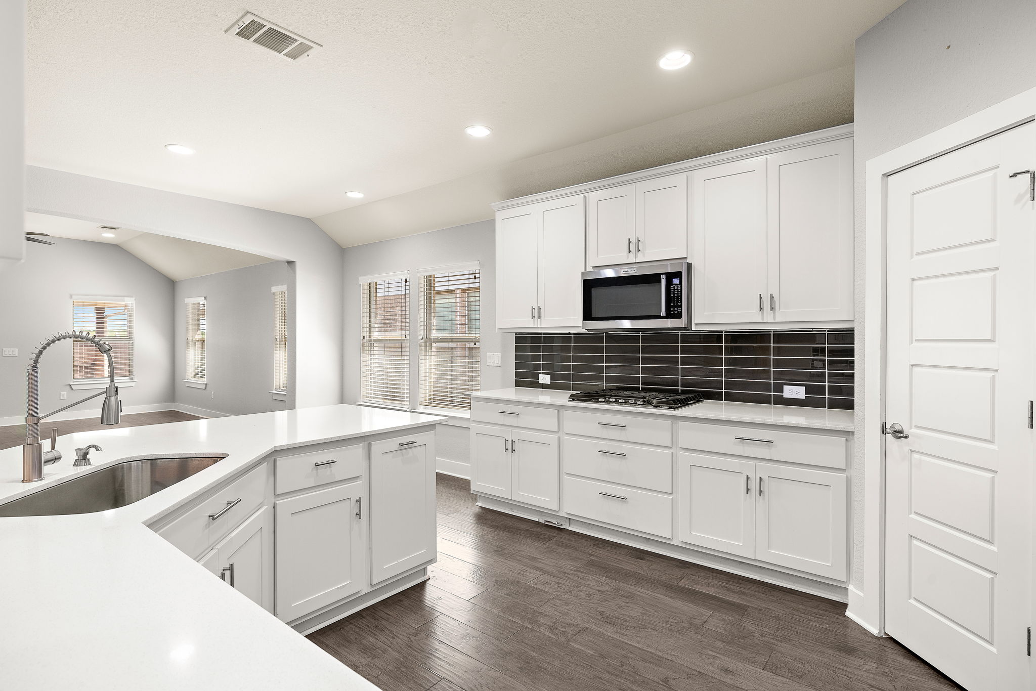 7520 Kinross Trail Austin, TX 78754 - Photo 13 of 37 Kitchen with white cabinets, dark wood-style flooring, recessed lighting, backsplash, and lofted ceiling
