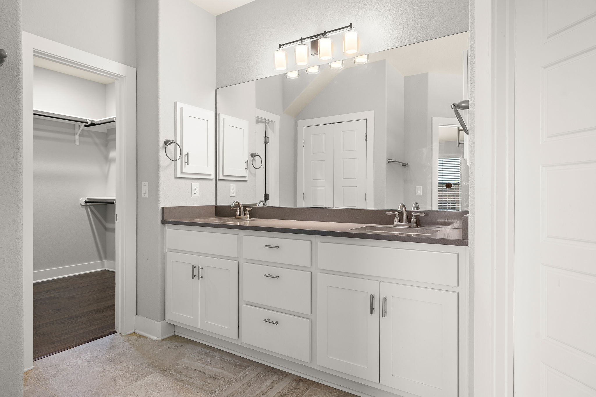 7520 Kinross Trail Austin, TX 78754 - Photo 16 of 37 Full bathroom featuring double vanity, a spacious closet, and light wood-type flooring