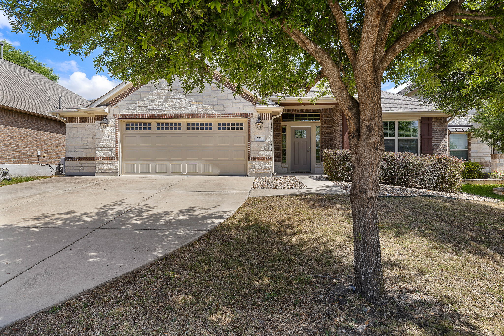 7520 Kinross Trail Austin, TX 78754 - Photo 2 of 37 Single story home featuring an attached garage, driveway, stone siding, and a front yard