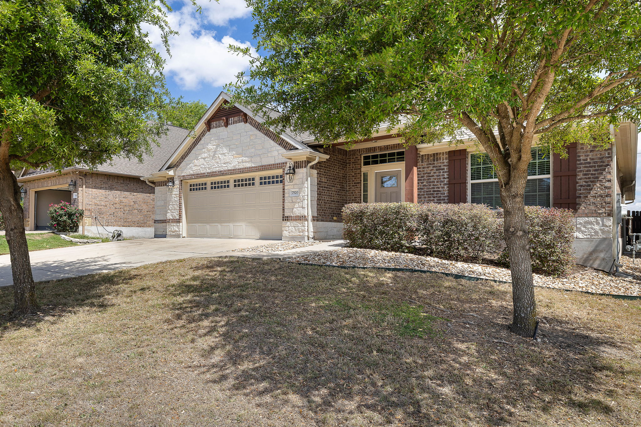 7520 Kinross Trail Austin, TX 78754 - Photo 3 of 37 View of front facade featuring an attached garage, driveway, stone siding, and brick siding