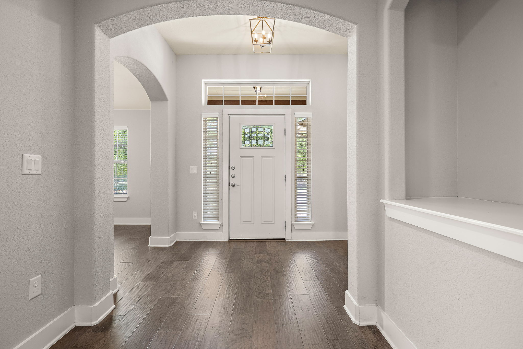 7520 Kinross Trail Austin, TX 78754 - Photo 4 of 37 Foyer featuring a textured wall, dark wood-style flooring, arched walkways, and suspended lighting