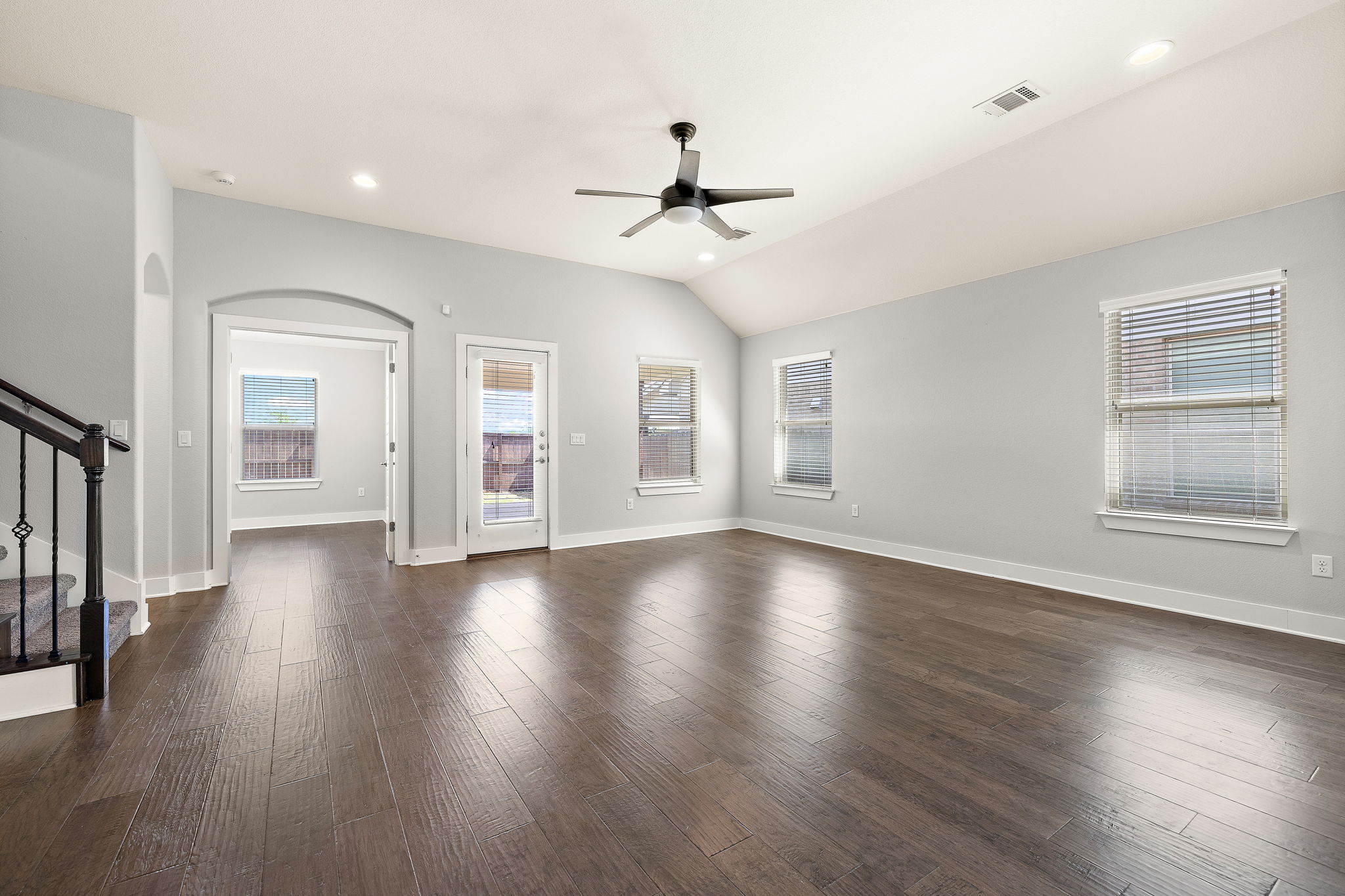 7520 Kinross Trail Austin, TX 78754 - Photo 9 of 37 Unfurnished living room with a ceiling fan, arched walkways, dark wood-style flooring, vaulted ceiling, and recessed lighting