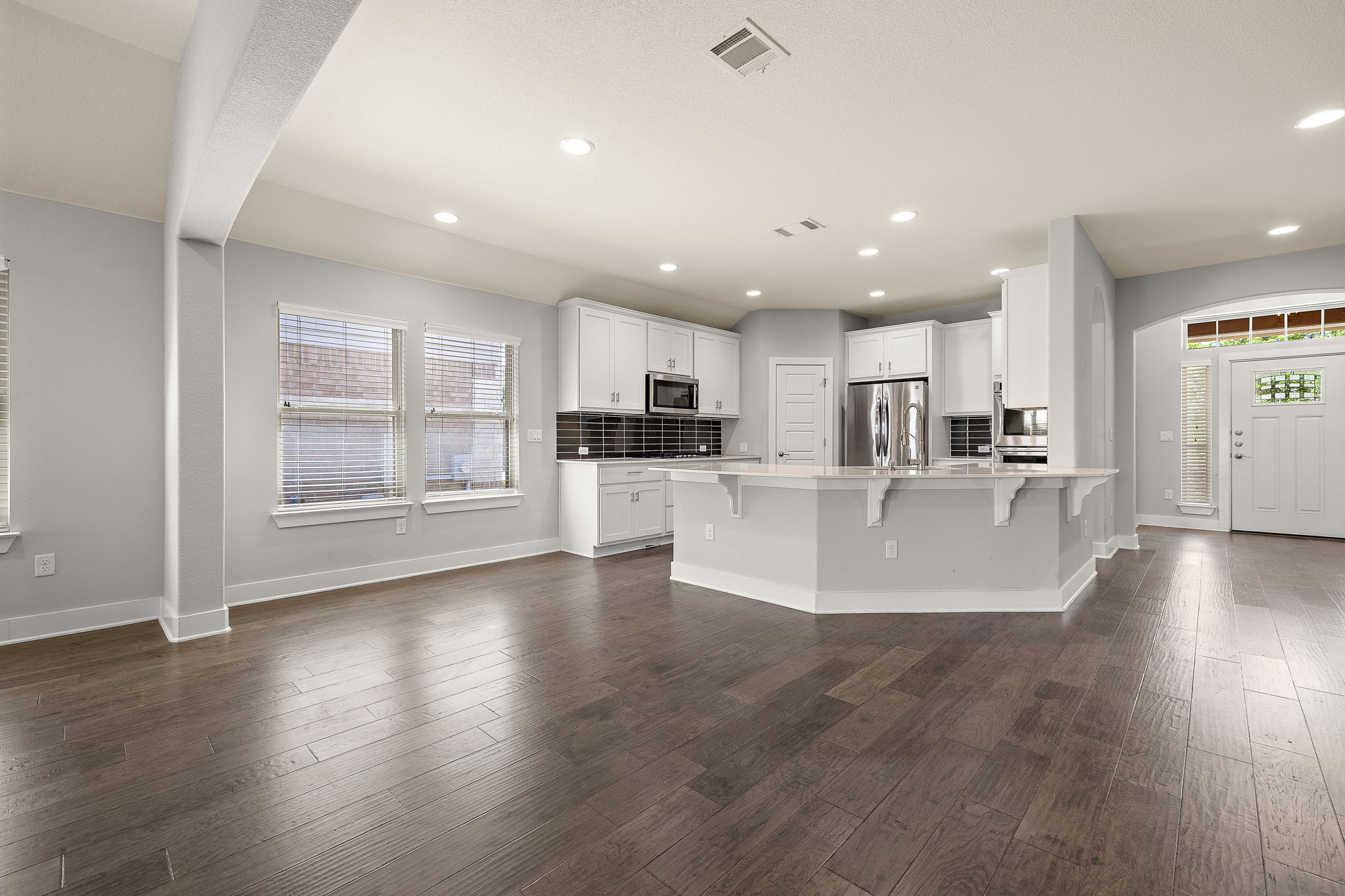 7520 Kinross Trail Austin, TX 78754 - Photo 10 of 37 Kitchen with a peninsula, a kitchen breakfast bar, white cabinets, stainless steel appliances, and dark wood-style floors