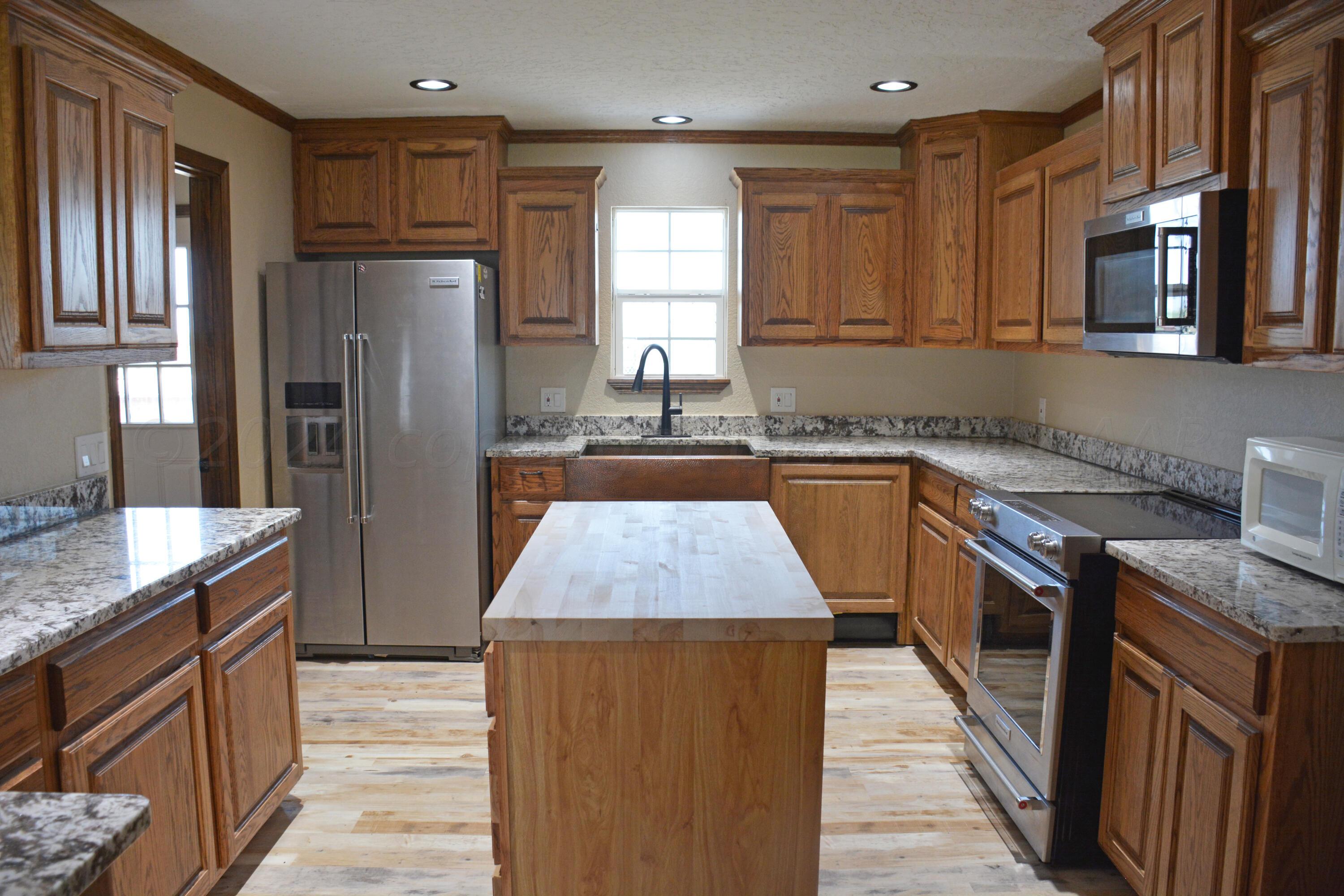 1159 Fm 1760 Muleshoe, TX 79347 - Photo 10 of 34 a kitchen with stainless steel appliances granite countertop wooden cabinets sink stove and refrigerator