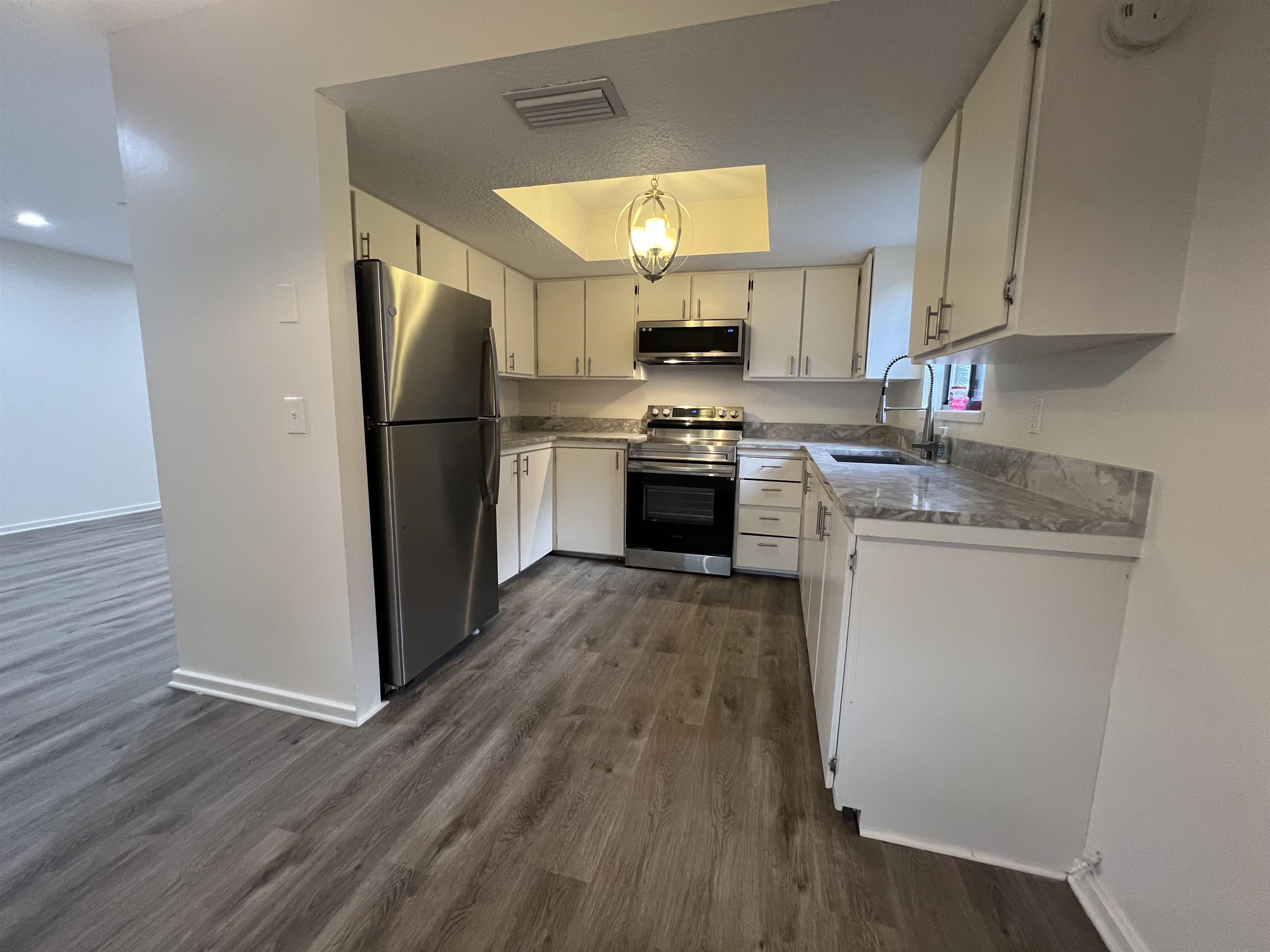 203 6th Street, Unit A St. Augustine, FL 32080 - Photo 15 of 21 a kitchen with a refrigerator a stove top oven a sink and wooden floor