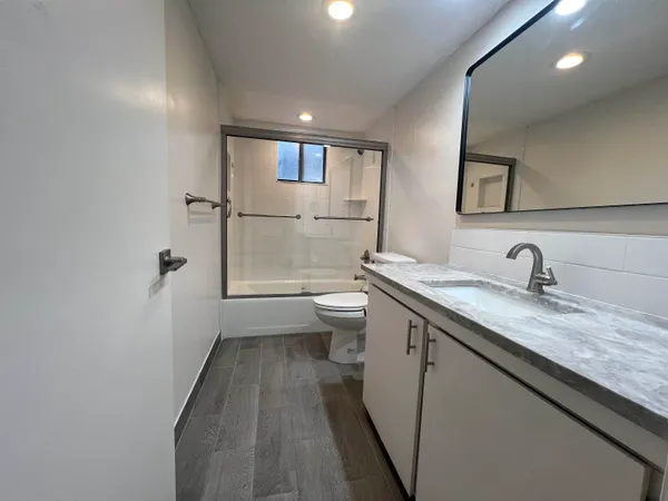 a bathroom with a granite countertop sink a toilet and a mirror