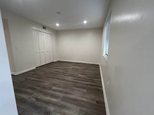 an empty room with wooden floor & windows