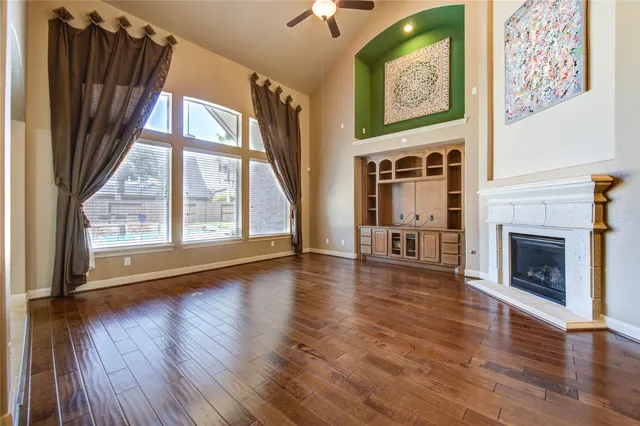 a view of an empty room with wooden floor fireplace and a window