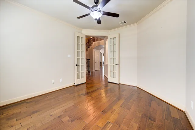 an empty room with wooden floor ceiling fan and windows