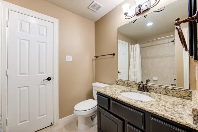 a bathroom with a granite countertop sink a toilet and a mirror