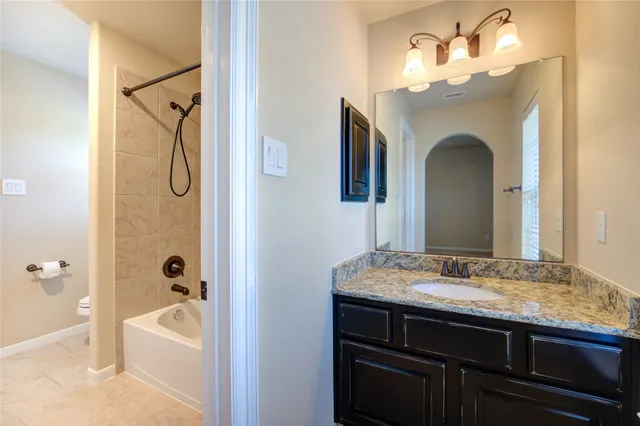 a en suite bathroom with a granite countertop sink and a mirror