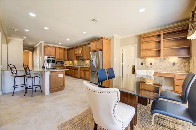 a kitchen with stainless steel appliances kitchen island granite countertop a refrigerator a stove a sink dishwasher a dining table and chairs with wooden floor