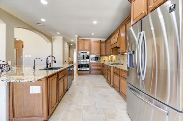 a kitchen with stainless steel appliances granite countertop a sink and a refrigerator