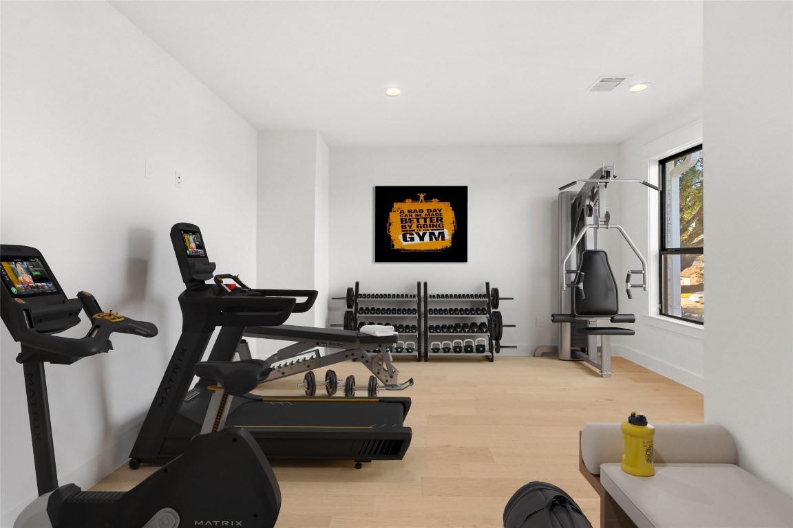 7115 Raton Street Houston, TX 77055 - Photo 18 of 49 This speakeasy room is virtually staged as a private home gym, highlighting how easily the space supports wellness-focused living. Clean white walls, wide-plank wood floors, and oversized windows create a bright, energizing environment that feels open and intentional. Whether you’re starting your day with a workout or reimagining the room as a studio, lounge, or office, this space adapts effortlessly to your lifestyle.