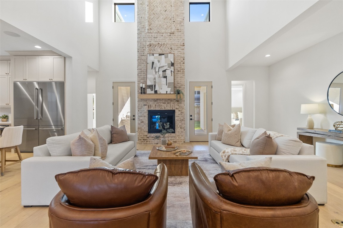 7115 Raton Street Houston, TX 77055 - Photo 3 of 49 Here, your living room comes together around the fireplace, with balanced seating that makes conversation feel easy and intentional. Tall windows and double-height ceilings flood the room with natural light, giving the entire space an airy, elevated feel throughout the day.