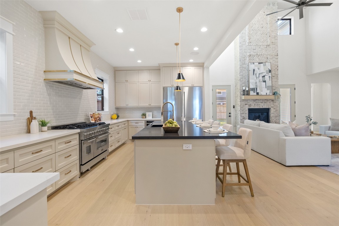 7115 Raton Street Houston, TX 77055 - Photo 4 of 49 This view captures how confidently your kitchen performs at scale. The professional gas range, statement vent hood, and wall-to-wall cabinetry create a true chef’s setup, while the long, uninterrupted counters give you room to prep, cook, and plate without ever feeling boxed in. Everything flows naturally toward the island, making this space equally suited for serious cooking or casual entertaining.