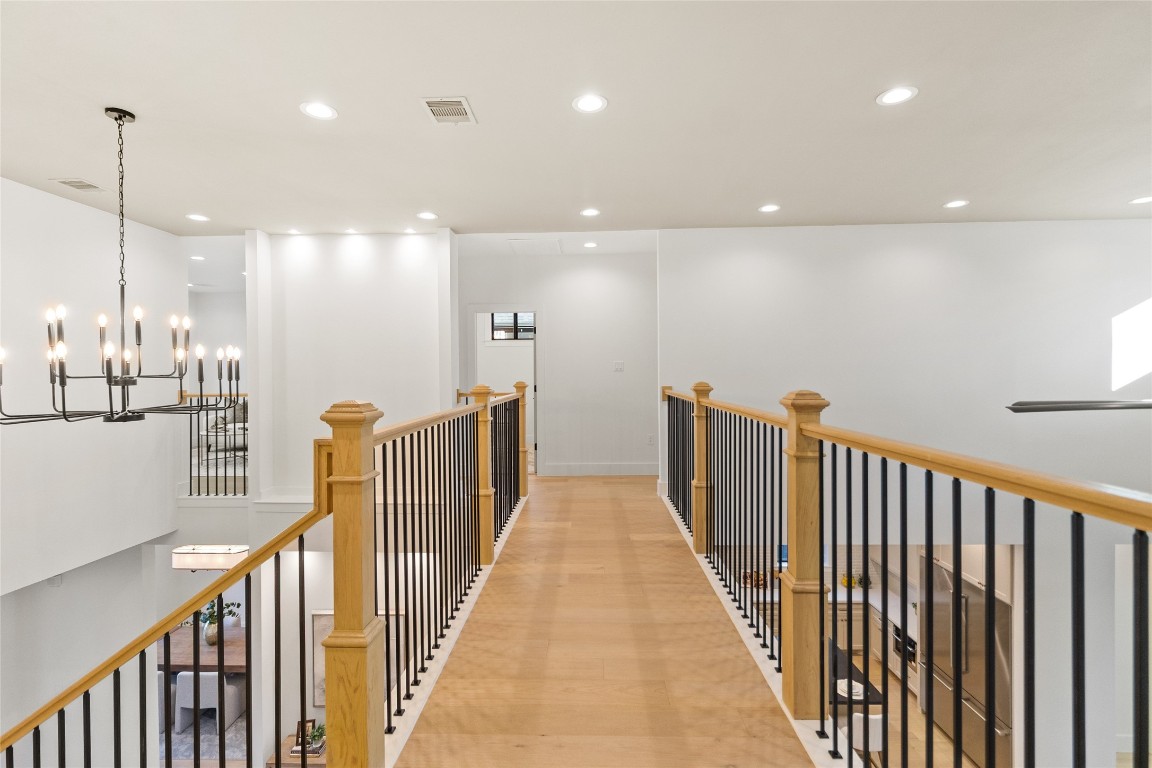 7115 Raton Street Houston, TX 77055 - Photo 42 of 49 The upstairs landing makes a statement with warm wood floors, natural wood railings, and black iron balusters that overlook the living space below. Recessed lighting keeps the area bright, and the open layout adds a sense of flow—perfect for a reading nook, gallery wall, or just enjoying the architectural depth of the home.