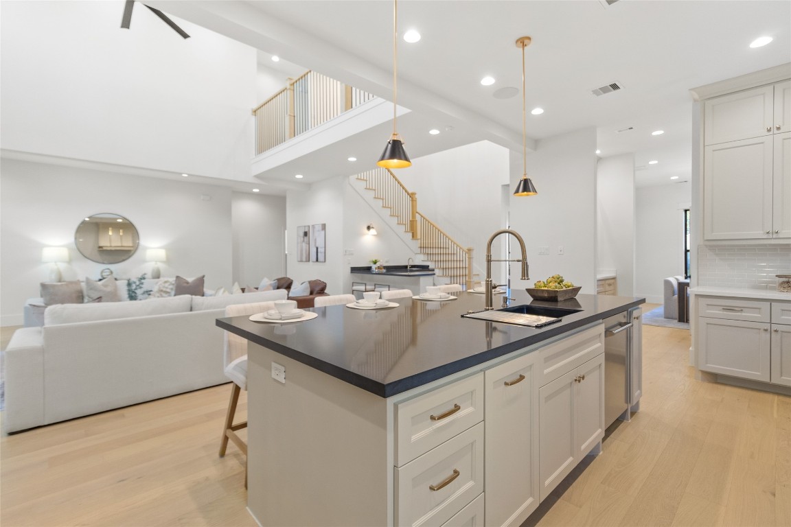 7115 Raton Street Houston, TX 77055 - Photo 7 of 49 Your oversized kitchen island anchors the heart of the home, giving you the perfect spot for morning coffee, casual meals, or hosting friends while still staying connected to the living room and staircase beyond. The sleek, dark countertops contrast beautifully with soft cabinetry and warm wood floors, while statement pendant lighting adds just the right touch of drama. Whether you’re plating dinner, pouring wine, or setting up for a game night, this space effortlessly keeps everything together.