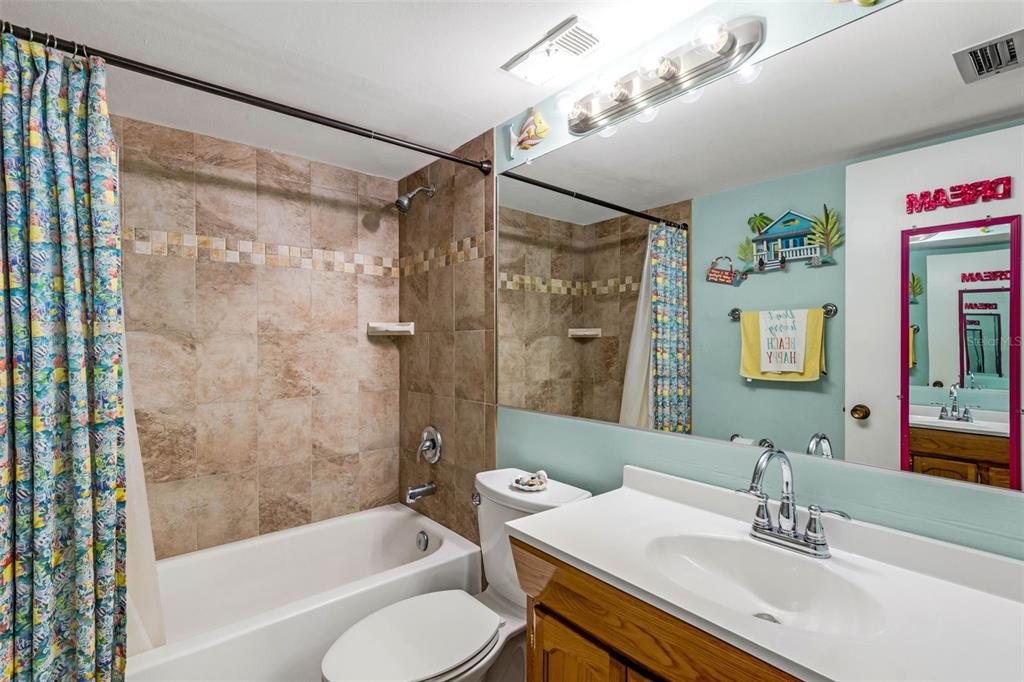 14900 Gulf Boulevard, Unit 410 Madeira Beach, FL 33708 - Photo 21 of 76 a bathroom with a granite countertop sink a mirror a bathtub and shower