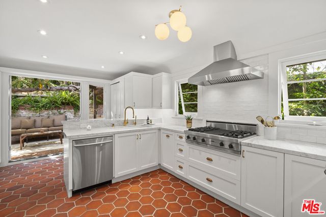 a kitchen with stainless steel appliances a refrigerator a sink a stove and white cabinets