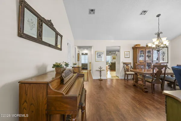 a view of a dining room and livingroom with furniture wooden floor a chandelier