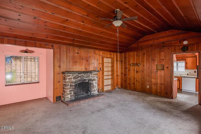 a view of an empty room with fireplace and a window