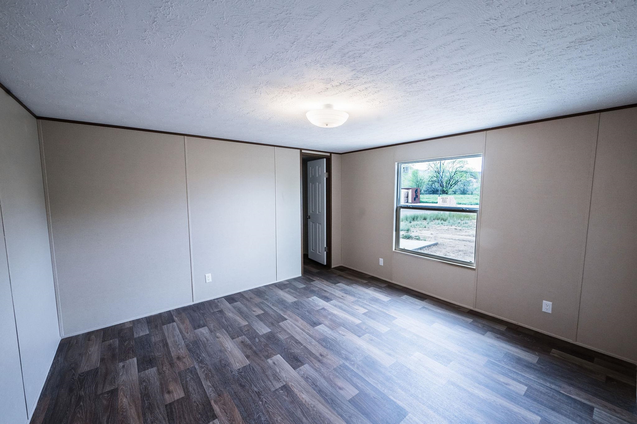283 Clements Way Fruita, CO 81521 - Photo 10 of 16 an empty room with wooden floor and windows