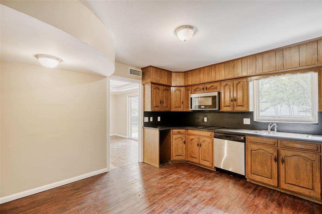 6612 East Mockingbird Lane Dallas, TX 75214 - Photo 11 of 28 a kitchen with stainless steel appliances granite countertop a sink cabinets and wooden floor