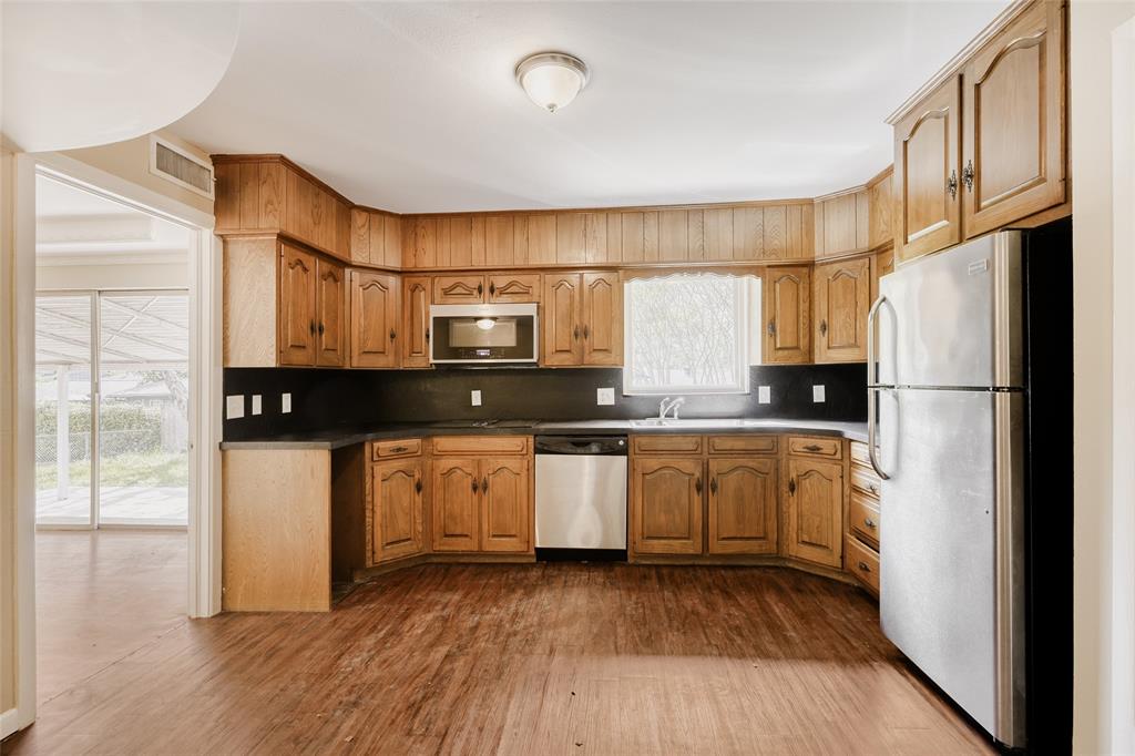 6612 East Mockingbird Lane Dallas, TX 75214 - Photo 10 of 28 a kitchen with stainless steel appliances granite countertop a refrigerator a stove a sink and white cabinets with wooden floor