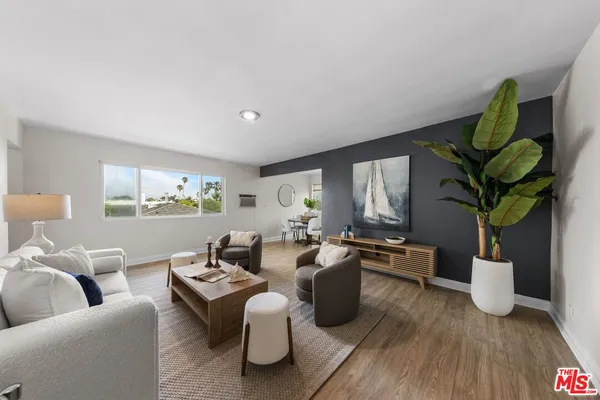 a living room with furniture a potted plant and a wooden floor
