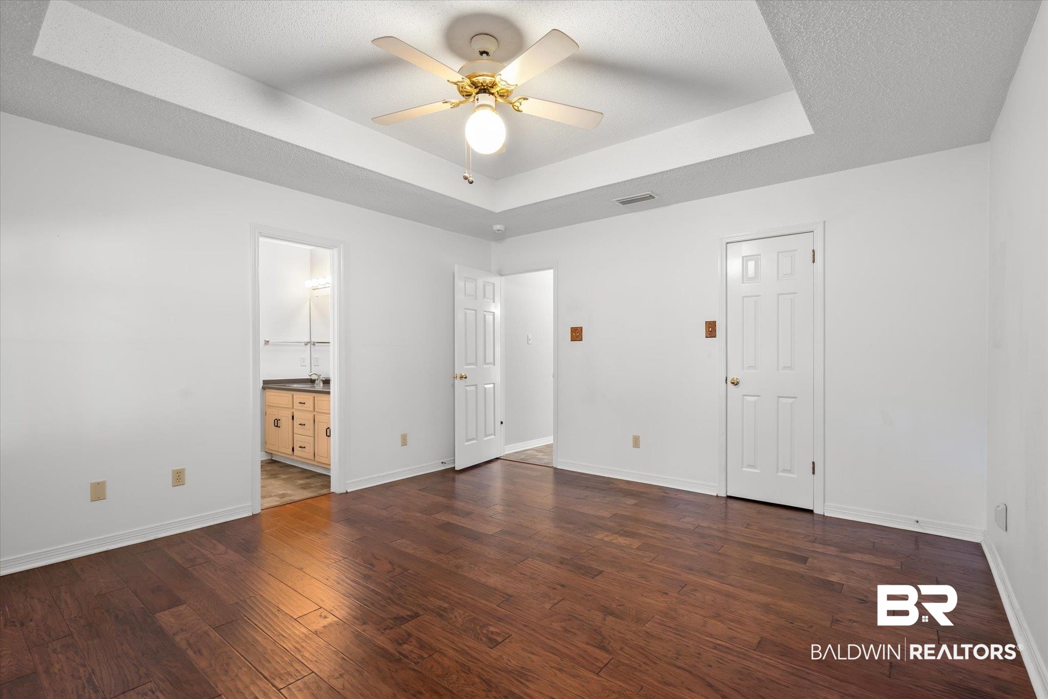 7410 East Lakeview Drive Mobile, AL 36695 - Photo 8 of 20 Unfurnished bedroom featuring connected bathroom, ceiling fan, dark hardwood / wood-style floors, a textured ceiling, and a tray ceiling