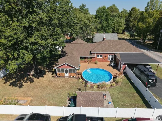 an aerial view of a house with a swimming pool and large trees