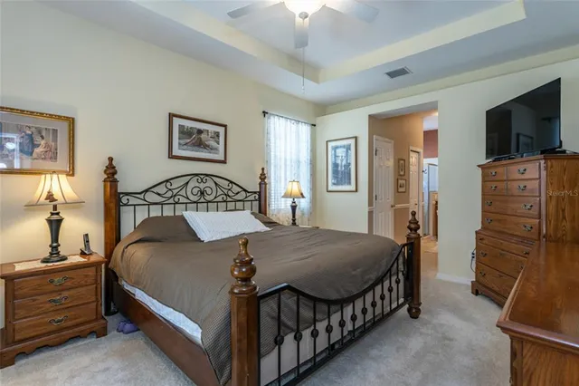 a bedroom with a bed a lamp on the dresser and a chandelier