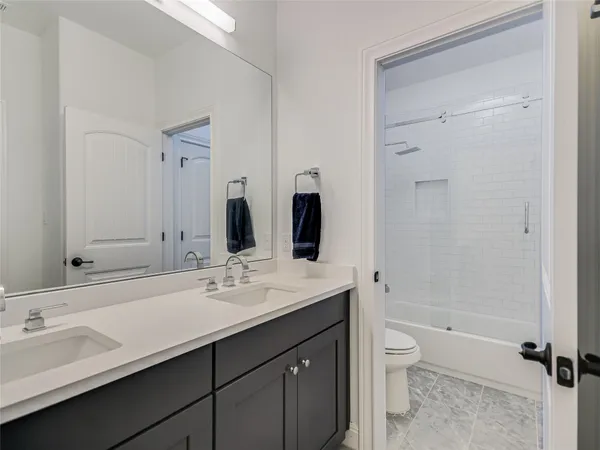 a bathroom with a double vanity sink toilet mirror and bathtub