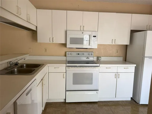 a kitchen with cabinets appliances a sink and a counter space