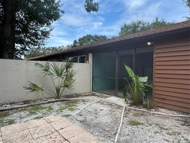 a backyard of a house with potted plants and large tree