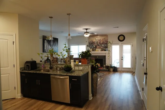 a kitchen with stainless steel appliances granite countertop a refrigerator a sink dishwasher a stove and white cabinets with wooden floor