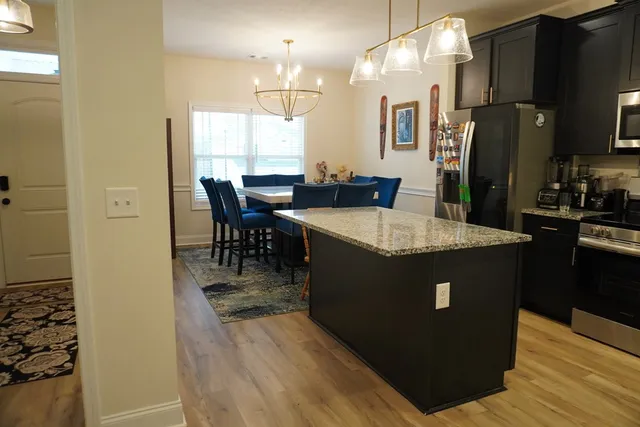 a kitchen with stainless steel appliances granite countertop a refrigerator a stove and a wooden floors