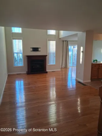 a view of an empty room with window and wooden floor